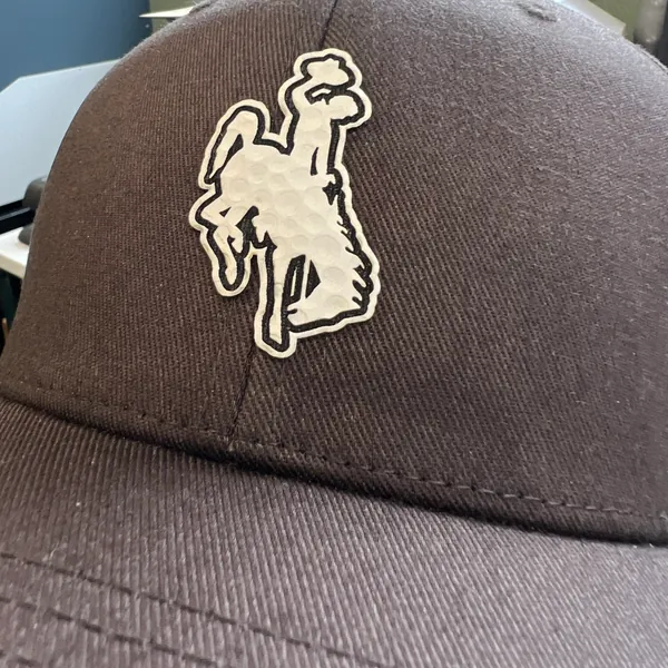 Brown cap with a white bucking horse patch with a golf ball texture