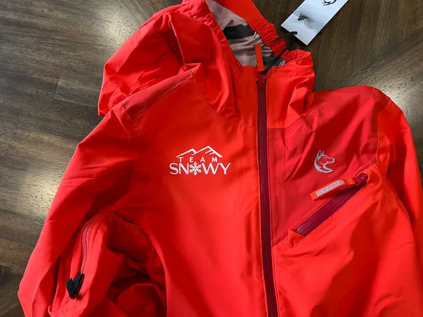 Red jacket with the white Team Snowy snowflake logo on the chest