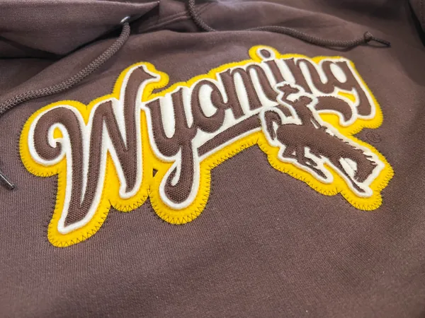 Brown hoodie with a Wyoming script appliqué and a bucking horse